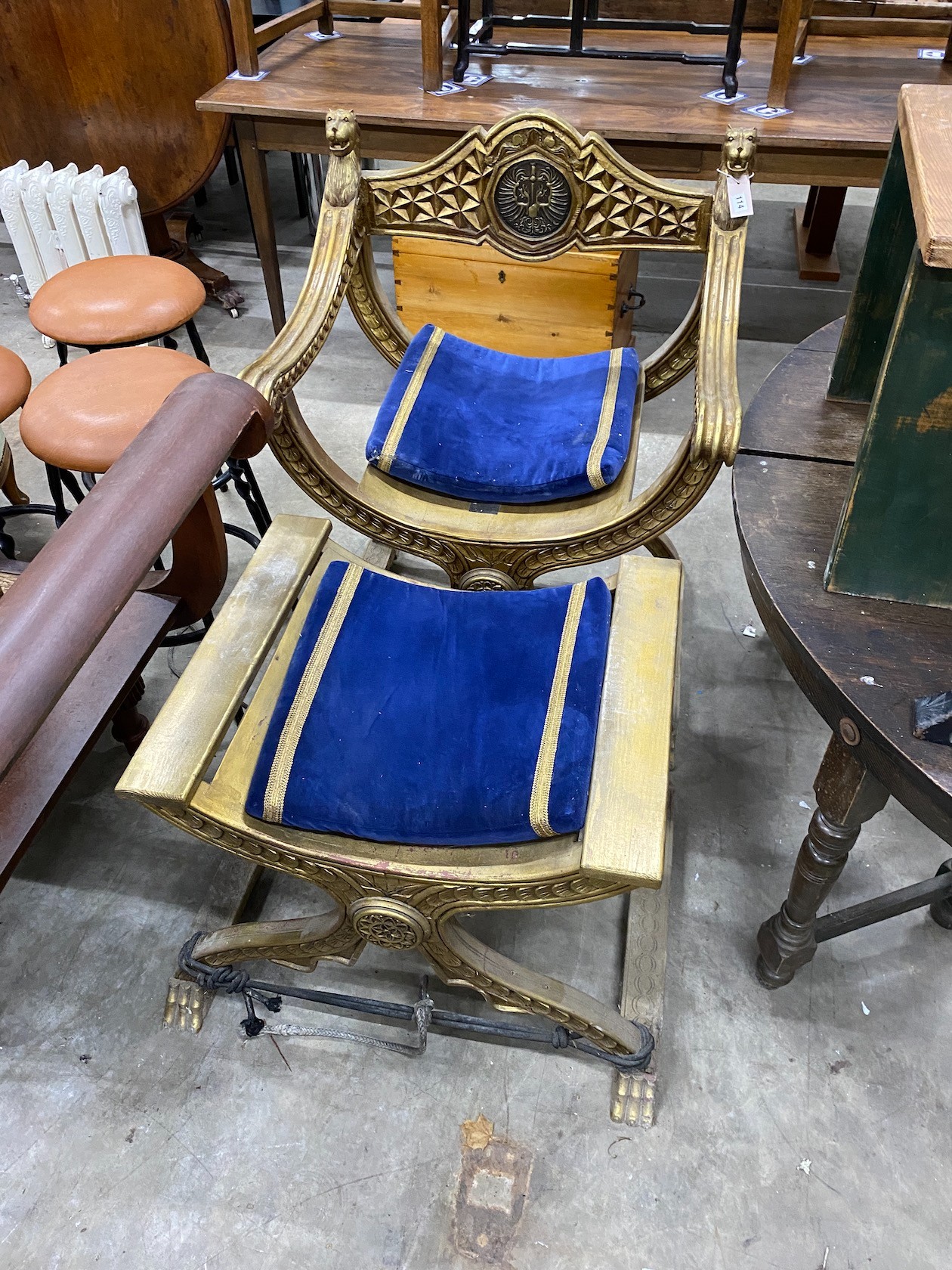A classical style gilt x-frame elbow chair, width 73cm, depth 52cm, height 96cm and a matching footstool